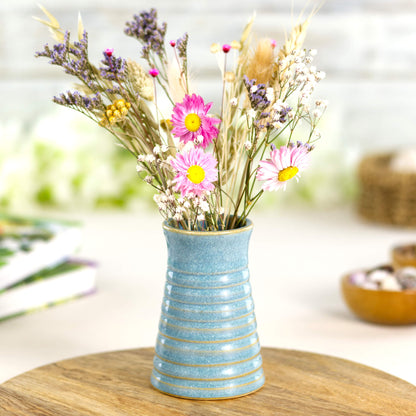 Coastal blue ribbed ceramic bud vase with small bouquet of colourful dried flowers. Floral display.