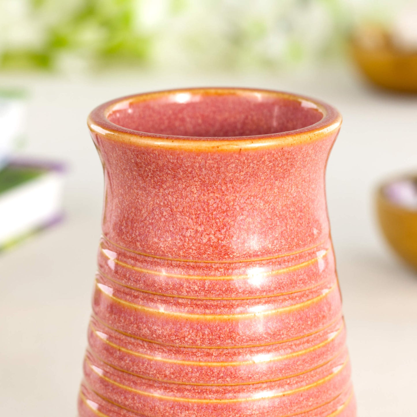 Close-up of a coral glazed ribbed ceramic bud vase highlighting its speckled texture and glossy finish.