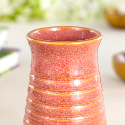 Close-up of a coral glazed ribbed ceramic bud vase highlighting its speckled texture and glossy finish.