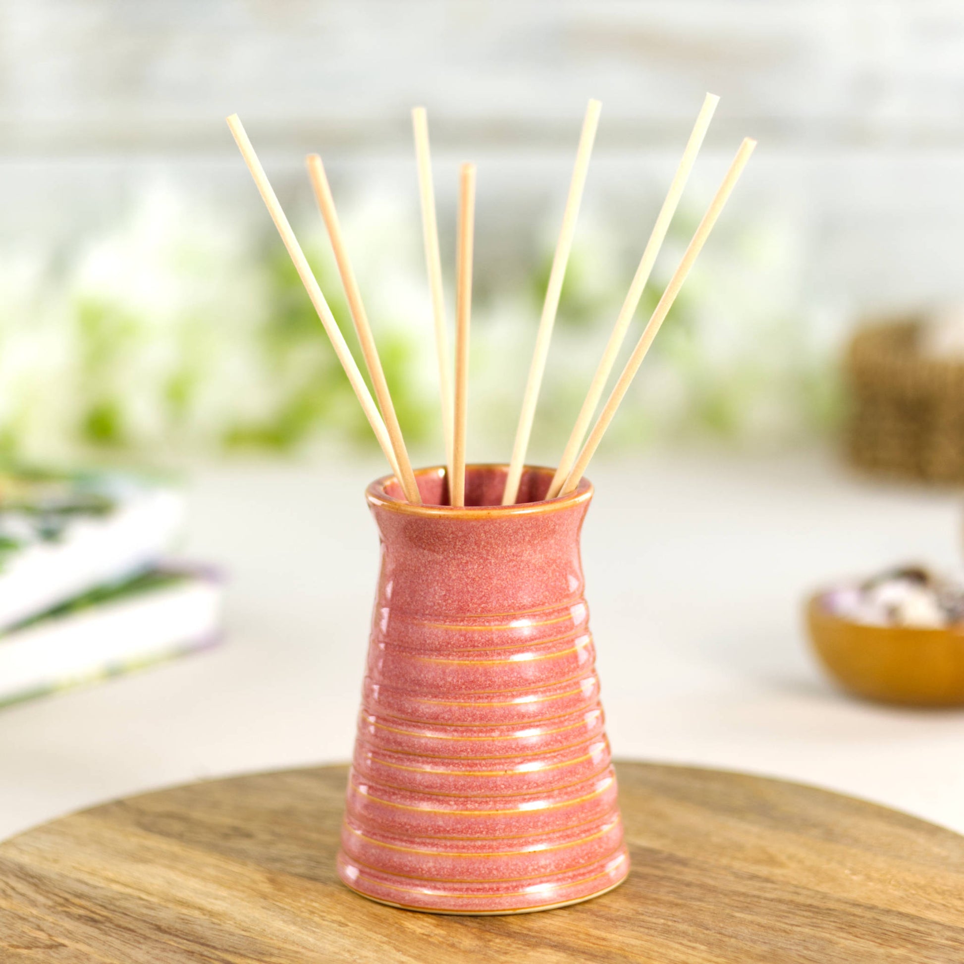 Coral ribbed ceramic bud vase used as a reed diffuser, combining fragrance with decorative elegance.