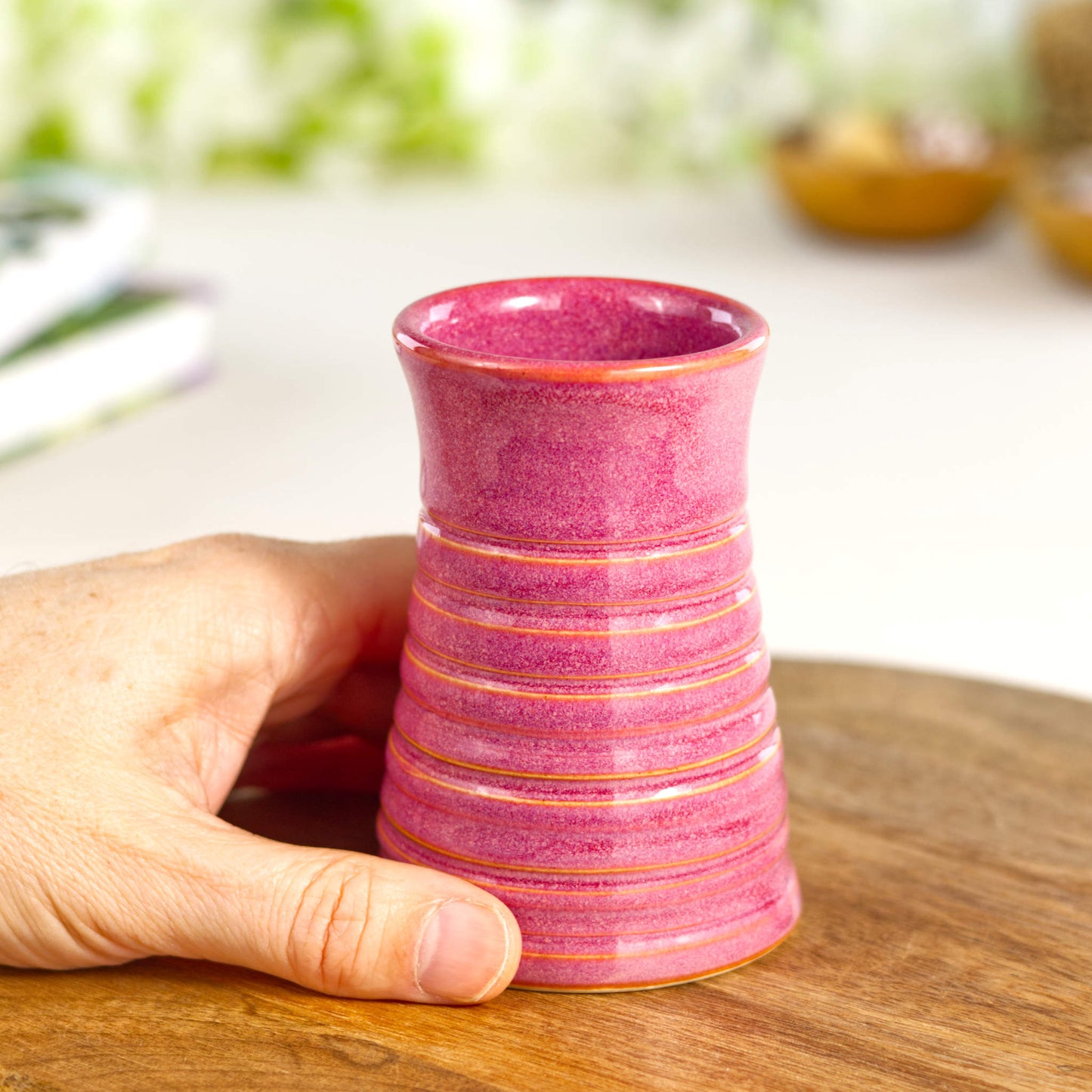 Crimson ribbed ceramic bud vase held in hand, illustrating its compact size and elegant proportions. Miniature Flower Vase.