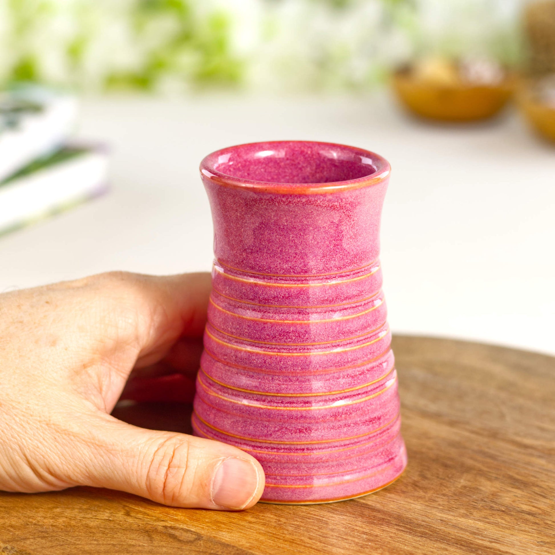 Crimson ribbed ceramic bud vase held in hand, illustrating its compact size and elegant proportions. Miniature Flower Vase.