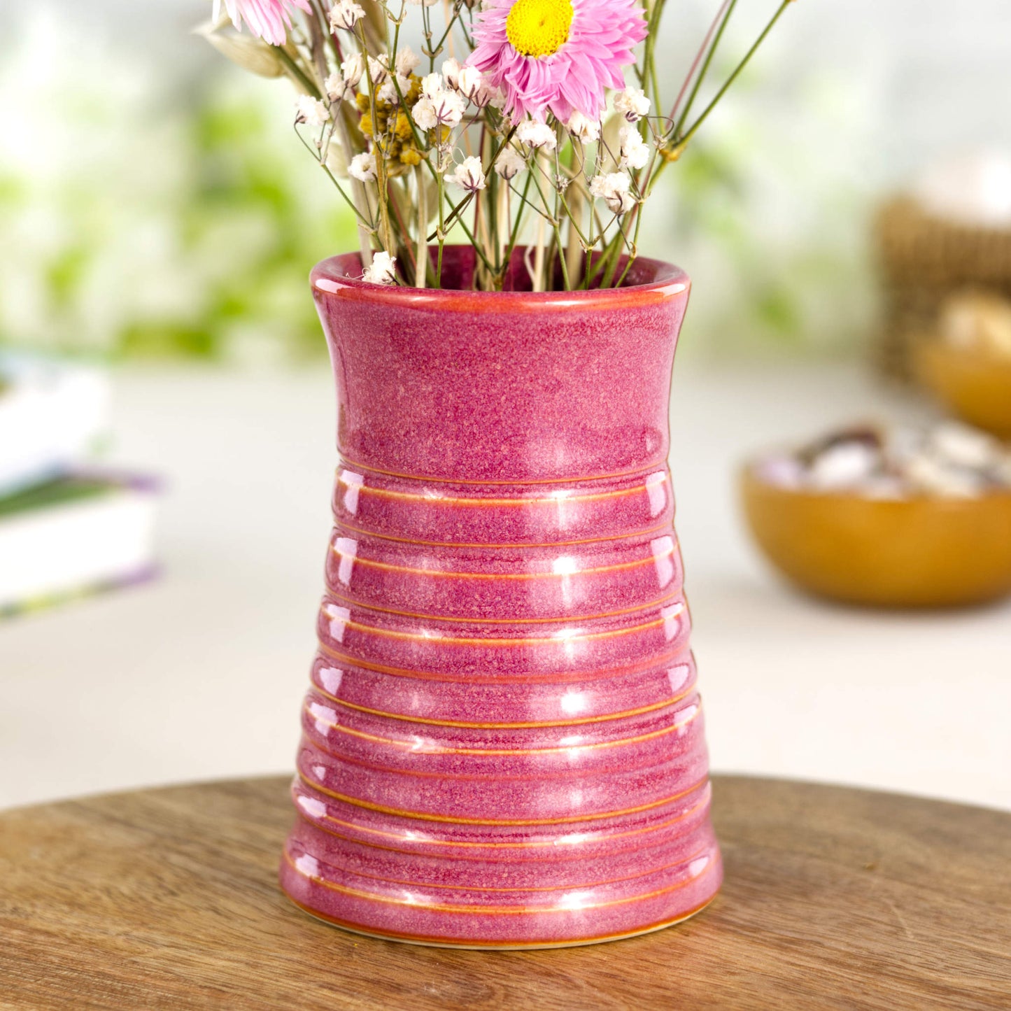 Crimson ribbed ceramic bud vase displayed on a wooden board, a striking accent for contemporary interiors.