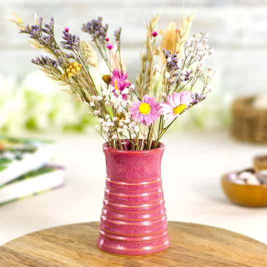 Crimson ribbed ceramic bud vase styled with colourful dried flowers, creating a vibrant decorative centrepiece.