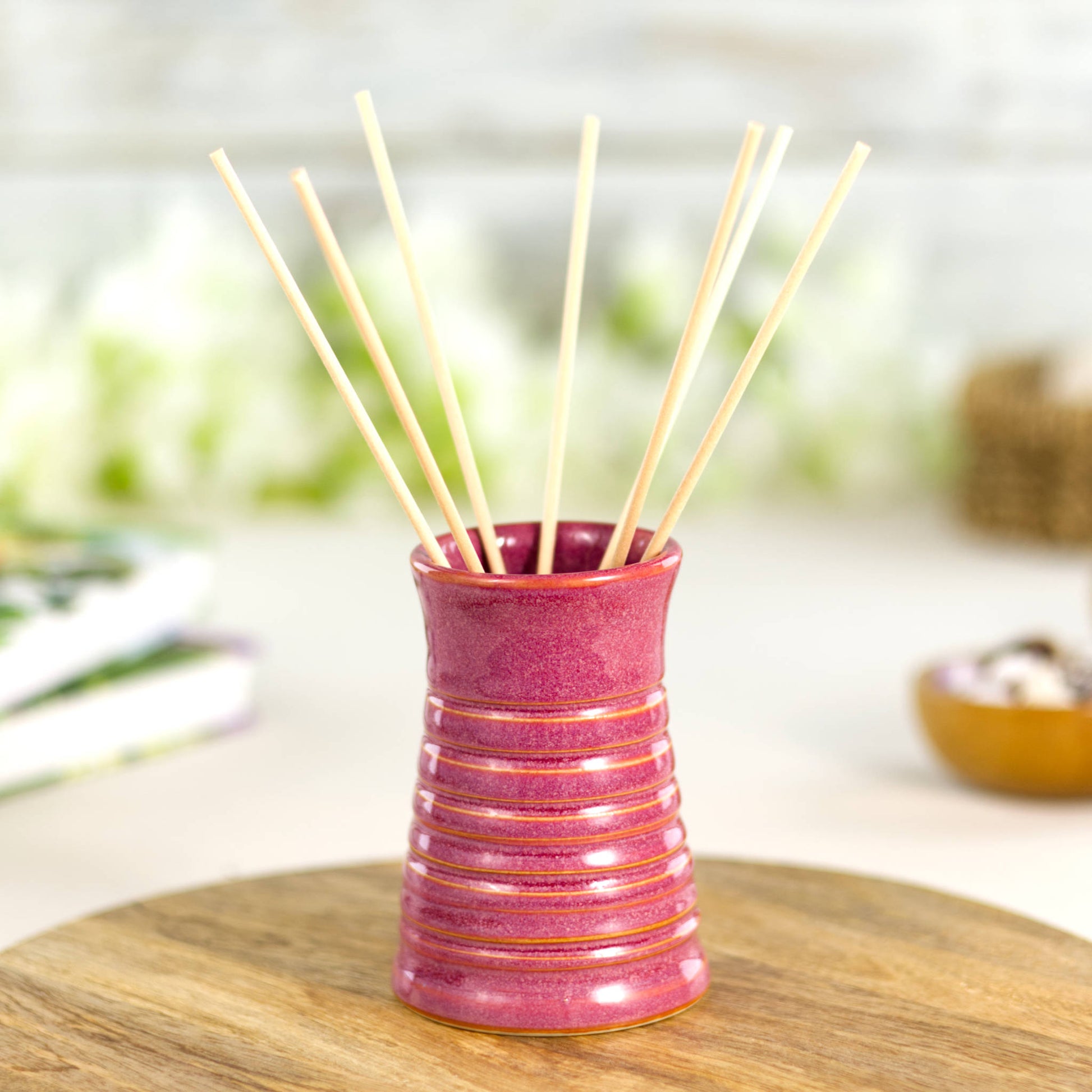 Crimson ribbed ceramic bud vase used as a reed diffuser, combining artisan craftsmanship with functional design.
