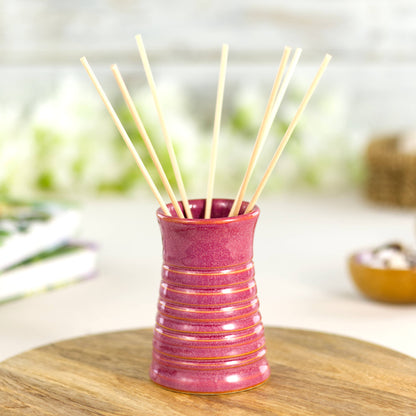 Crimson ribbed ceramic bud vase used as a reed diffuser, combining artisan craftsmanship with functional design.