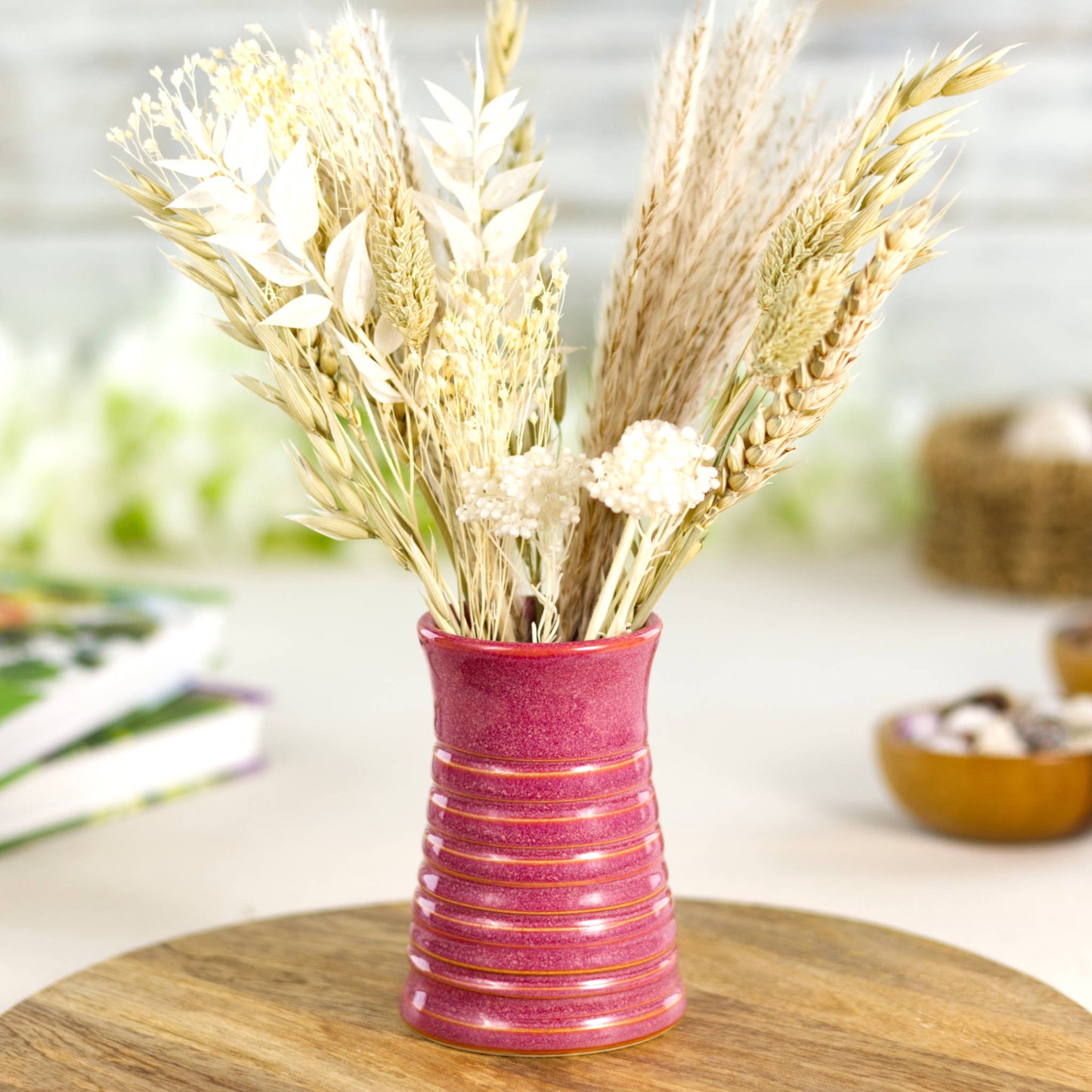 Crimson ribbed ceramic bud vase arranged with neutral dried grasses, ideal for warm, rustic interior styling.