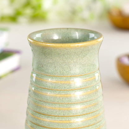 Close-up of a pale green ribbed ceramic bud vase in Sea Smoothed Pebble glaze with a glossy speckled finish.