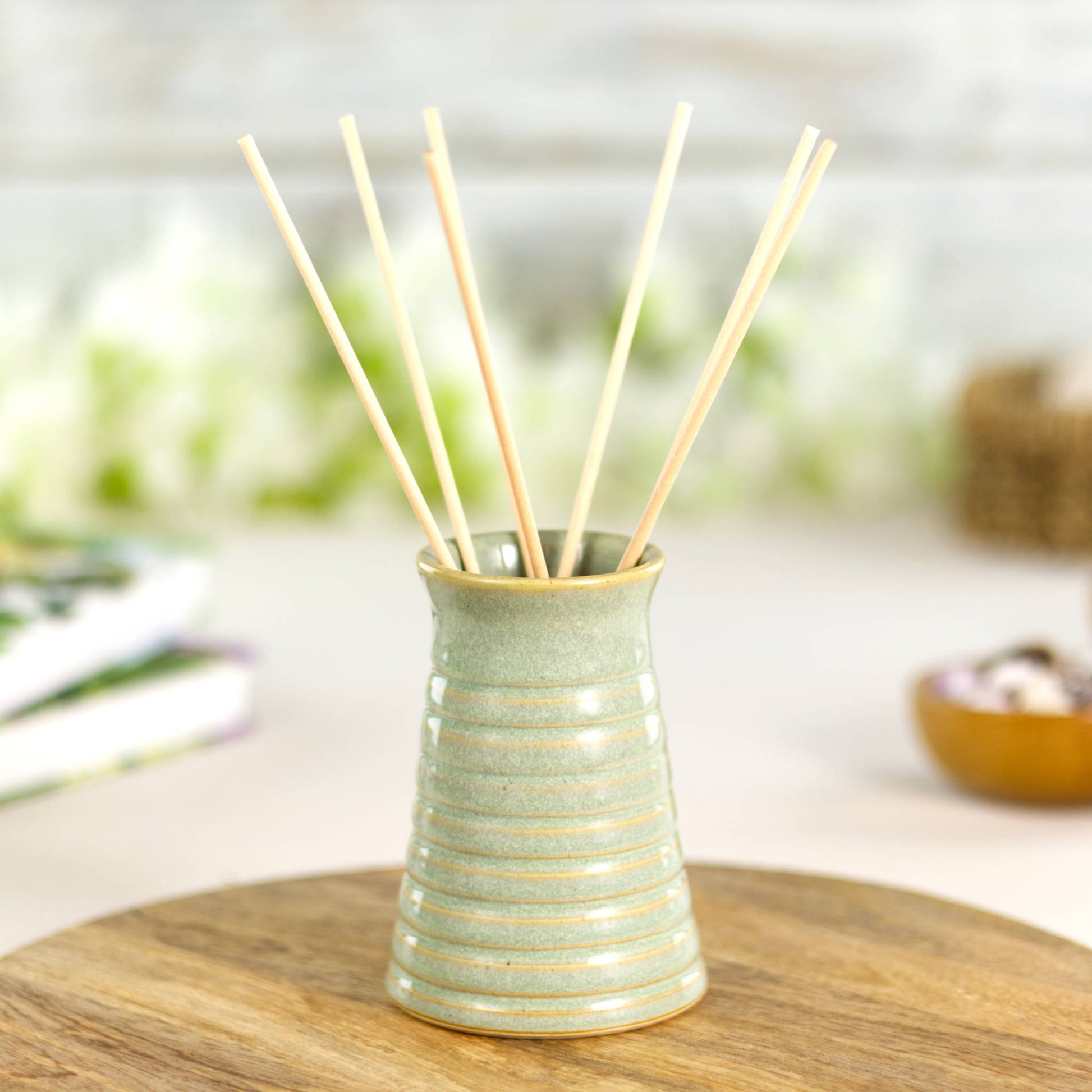 Pale green ribbed ceramic bud vase styled with natural reeds, suitable as a decorative reed diffuser vase.