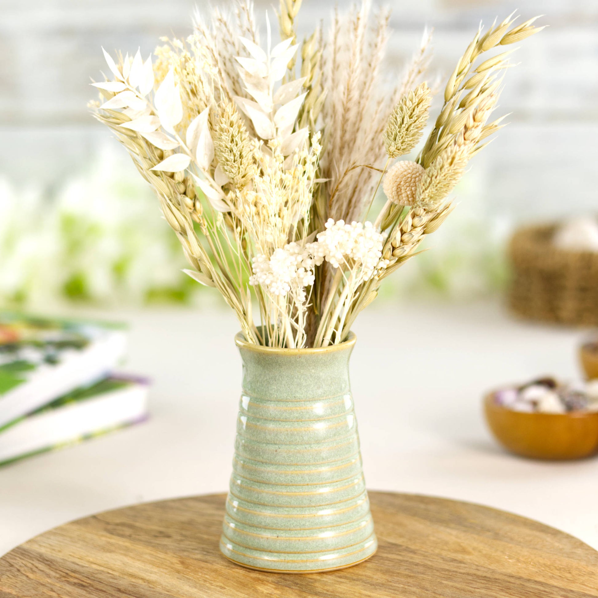 Handmade pale green ribbed ceramic bud vase with neutral dried flowers, ideal for Scandinavian-inspired décor.