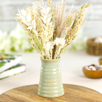 Handmade pale green ribbed ceramic bud vase with neutral dried flowers, ideal for Scandinavian-inspired décor.