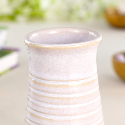 Close-up of a handmade white ribbed ceramic bud vase with a soft white wabi sabi style glaze and subtle tonal variation.