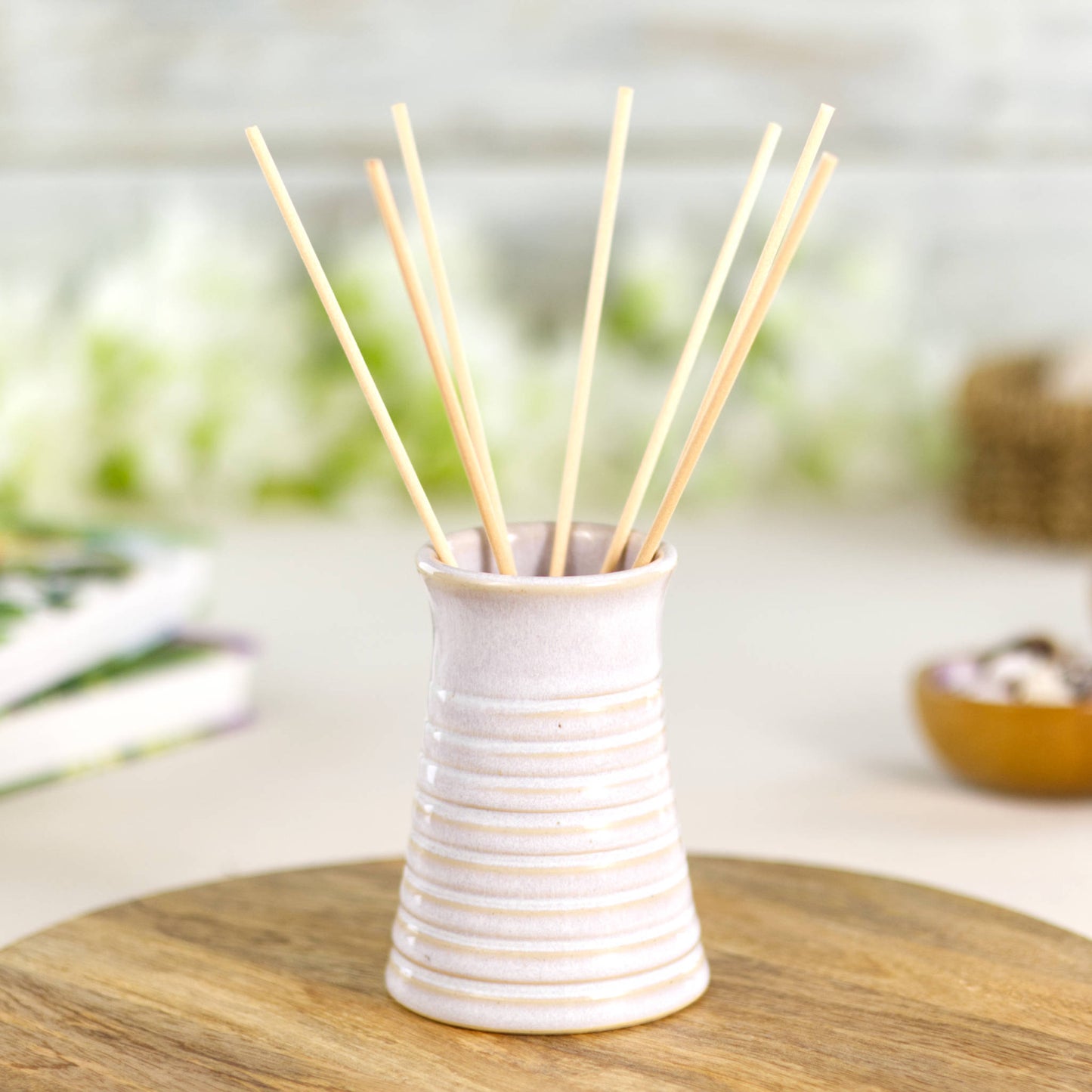 White ribbed ceramic bud vase used as a reed diffuser, ideal for serene and minimalist home styling.