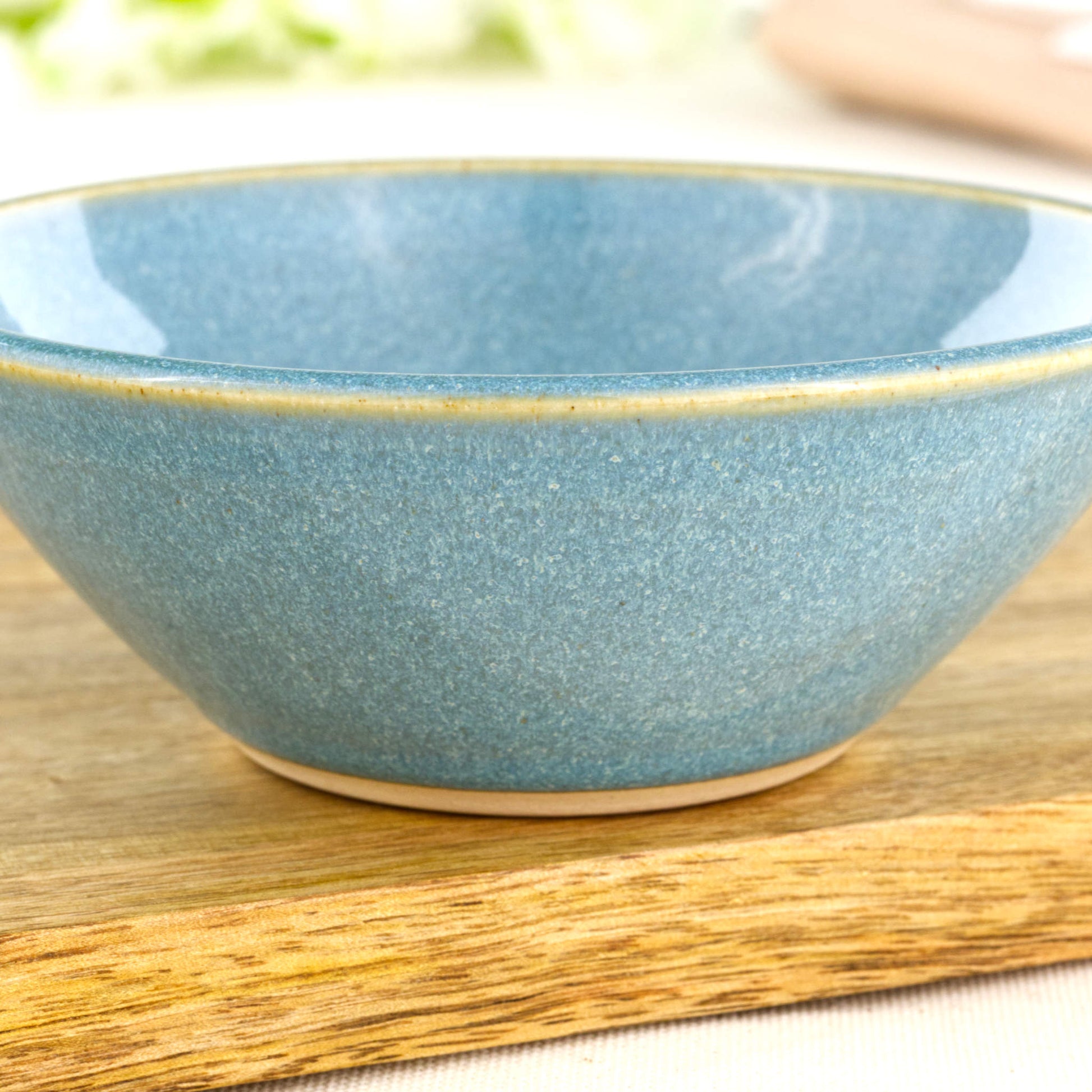 Close-up of Coastal Blue Sea Smoothed Pebble glaze on a wheel-thrown small bowl, showing natural speckling and glossy finish