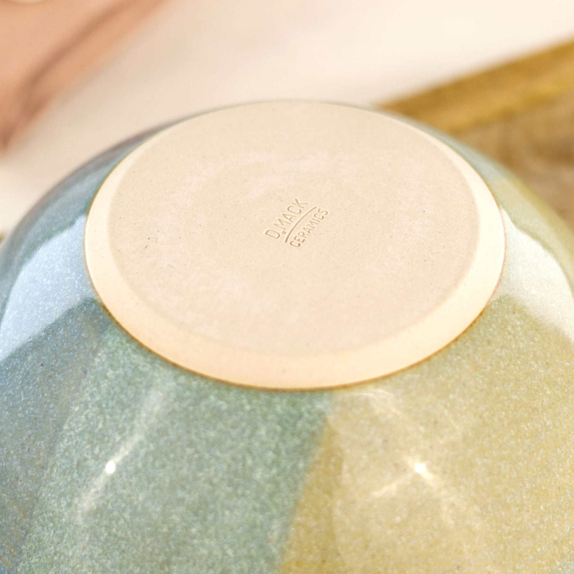 Base of Blue and Green handmade small bowl showing my maker’s mark and smooth burnished foot, designed to help reduce surface scratching on tables and worktops