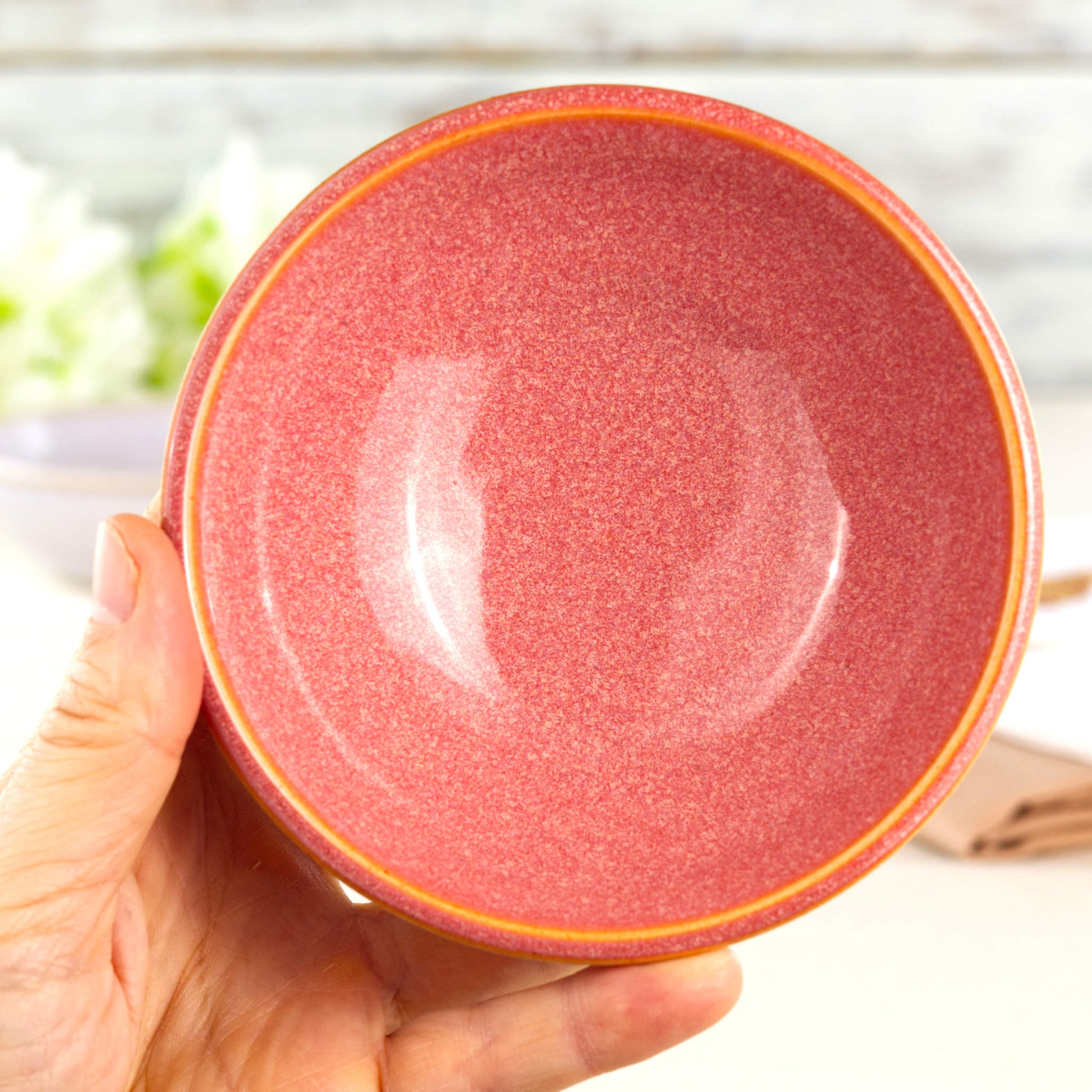 Coral handmade ceramic bowl held in hand, a small dip bowl for hummus, guacamole, sauces and party snacks