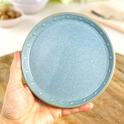 Handmade Coastal Blue small plate held in the hand, a wheel-thrown stoneware side plate from a small British pottery studio