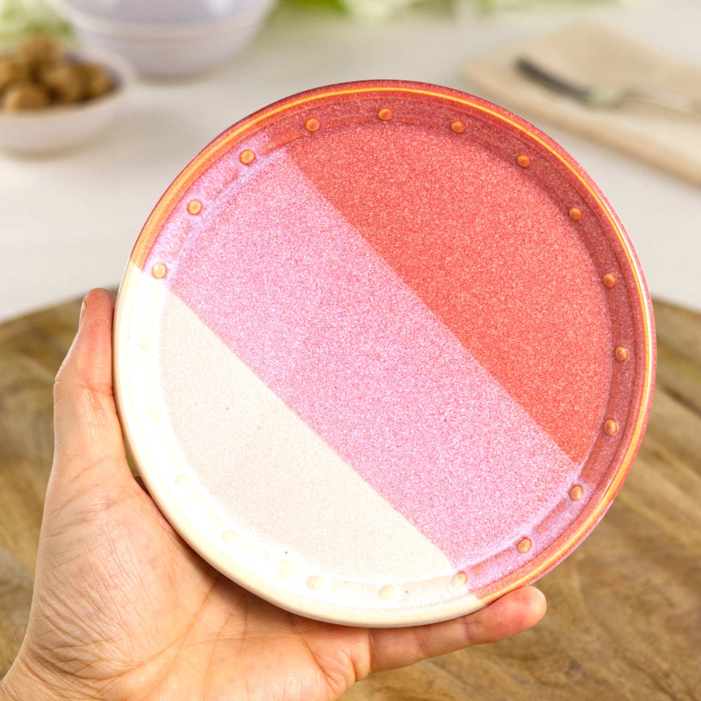 Handmade Coral & White small plate held in the hand, a wheel-thrown stoneware side plate from a British artisan studio