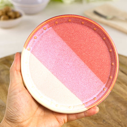 Handmade Coral & White small plate held in the hand, a wheel-thrown stoneware side plate from a British artisan studio