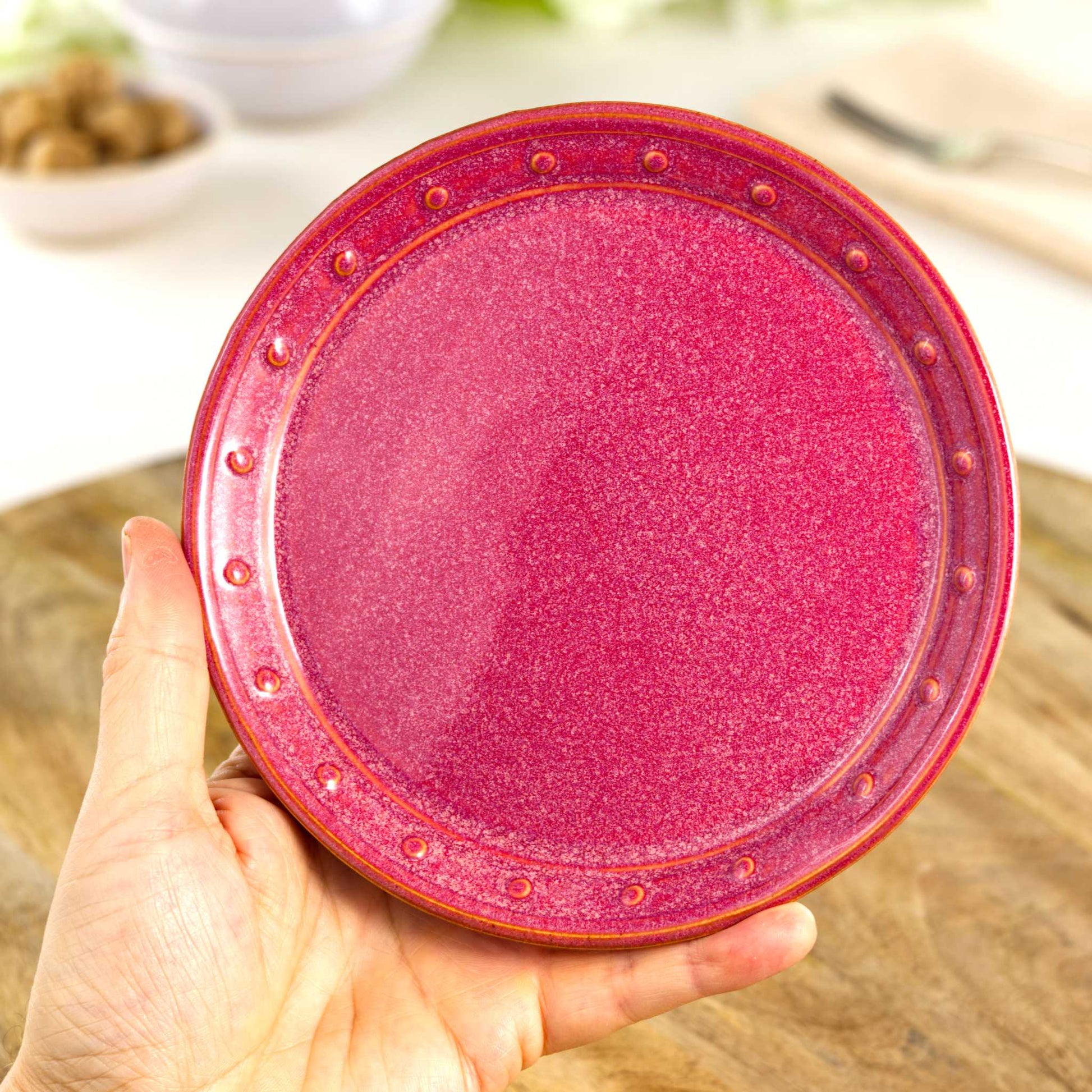 Handmade Crimson small plate held in the hand, a wheel-thrown stoneware side plate from a small British artisan studio