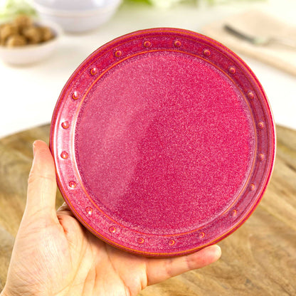 Handmade Crimson small plate held in the hand, a wheel-thrown stoneware side plate from a small British artisan studio