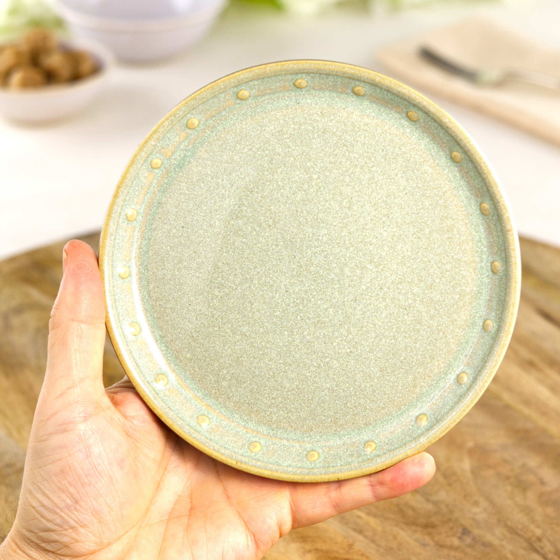 Handmade Pale Green small plate held in the hand, a wheel-thrown stoneware side plate from a small British artisan studio