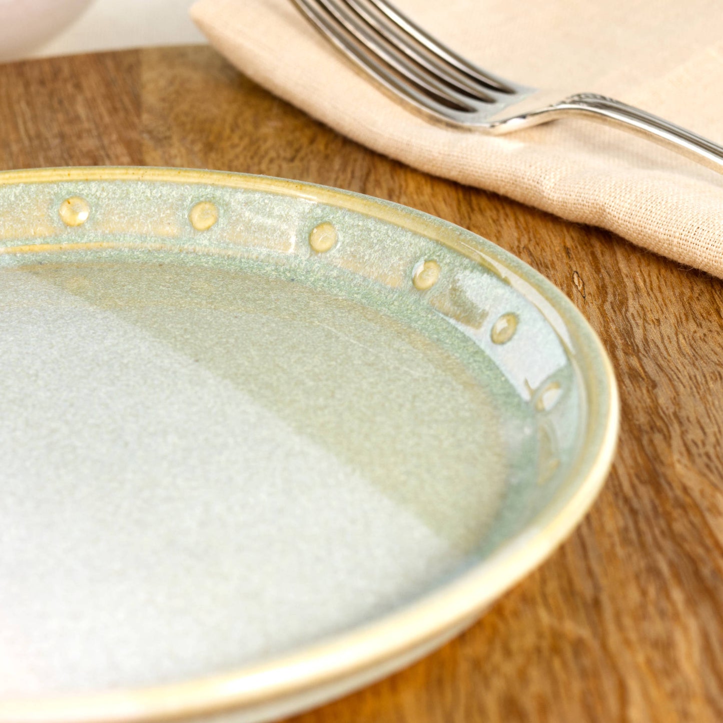 Close-up of a Pale Green & White ceramic small plate, highlighting the glossy speckled glaze, soft green tones and hand-finished dotted rim detail