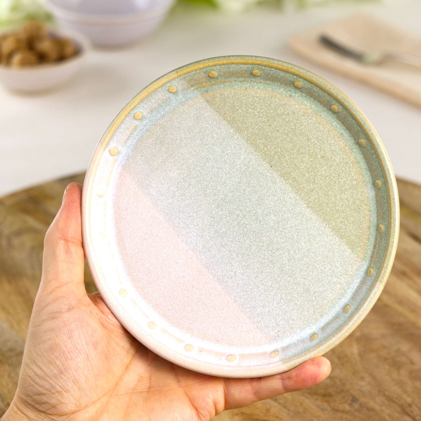 Handmade Pale Green & White small plate held in the hand, a wheel-thrown stoneware side plate from a British studio pottery range
