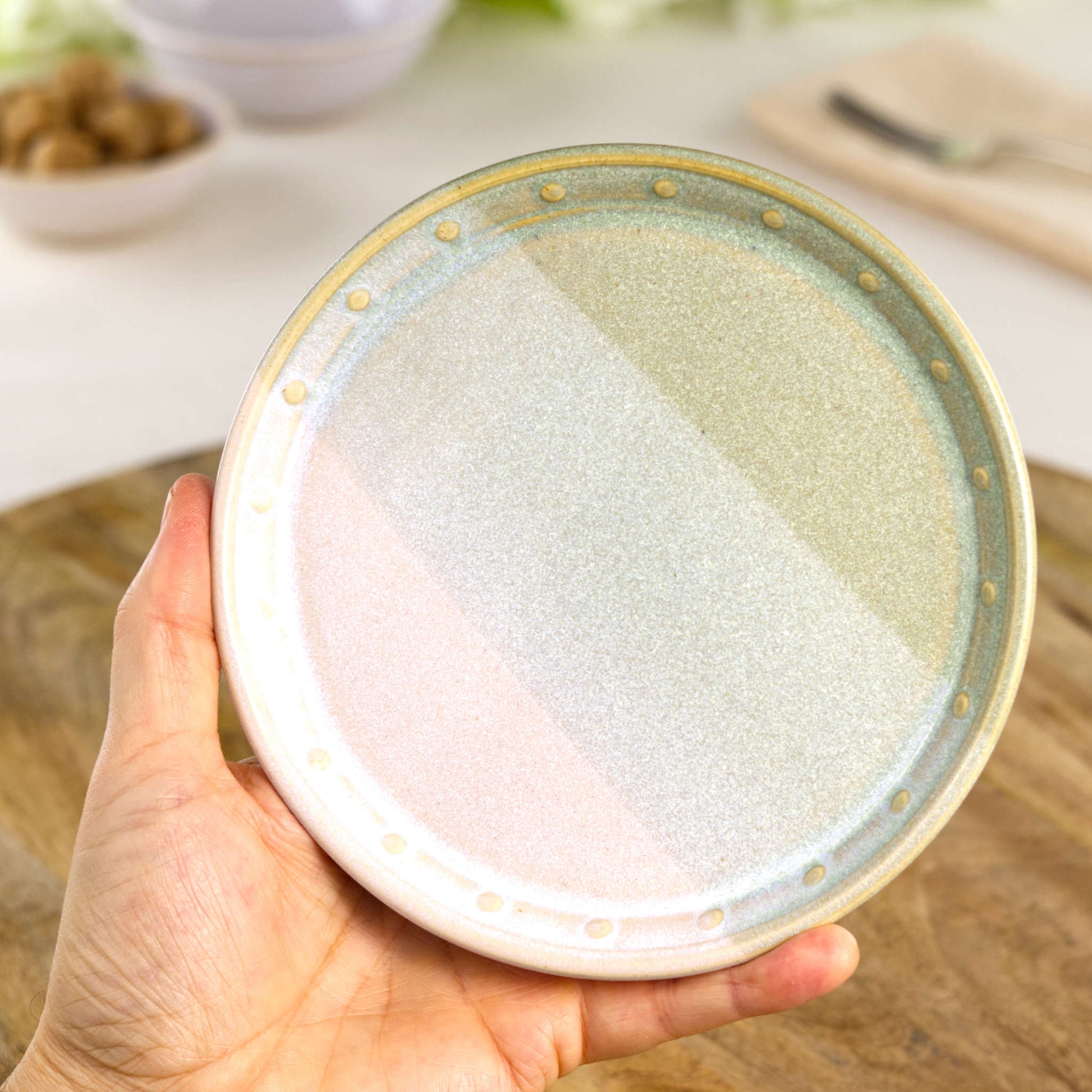 Handmade Pale Green & White small plate held in the hand, a wheel-thrown stoneware side plate from a British studio pottery range