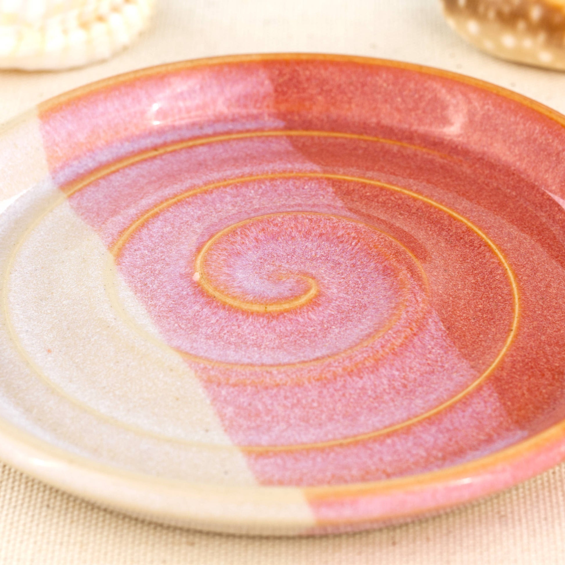 Close up of coral and white soap dish, overlapping glazes with spiral ridges and glossy double dipped finish