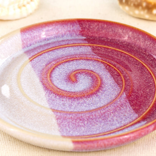 Close up of crimson and white soap dish, overlapping glazes with spiral ridges and glossy double dipped finish