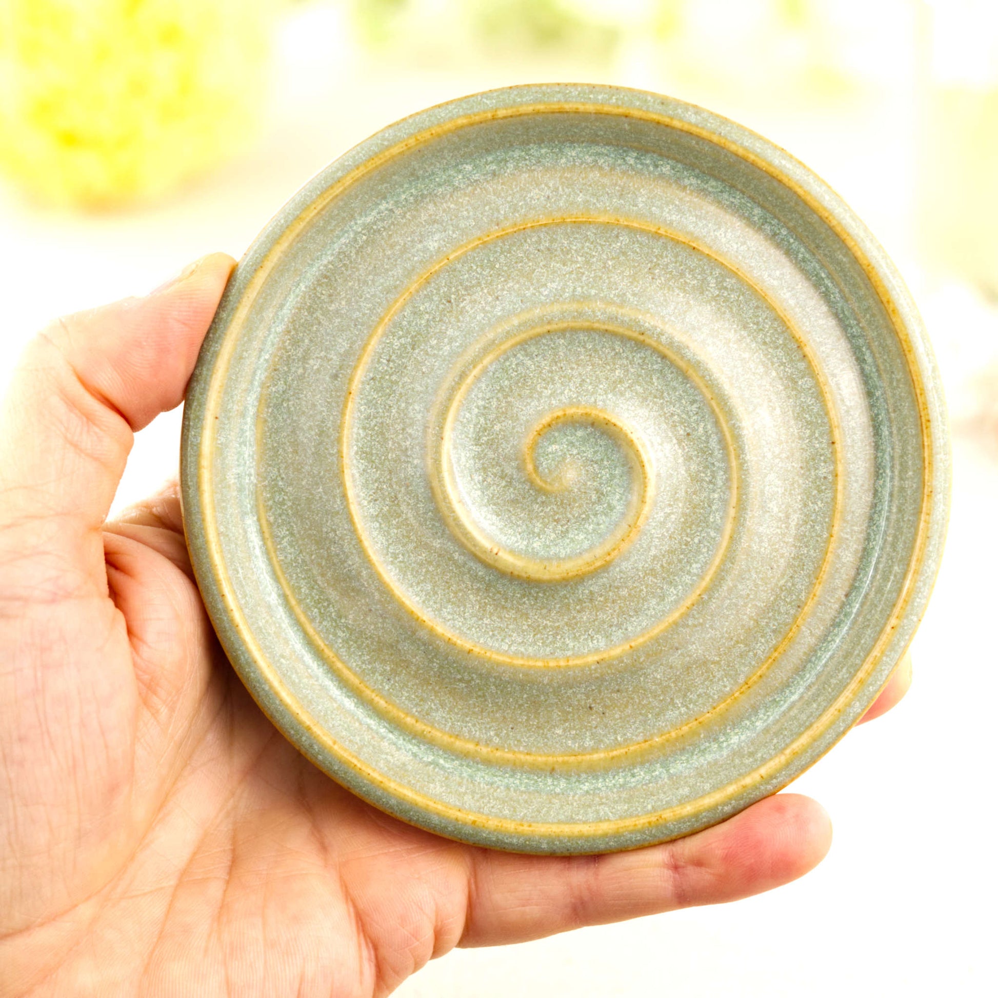Pale green pottery soap dish held in hand showing compact bathroom size
