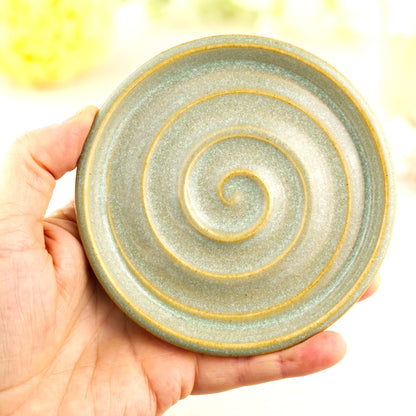 Pale green pottery soap dish held in hand showing compact bathroom size