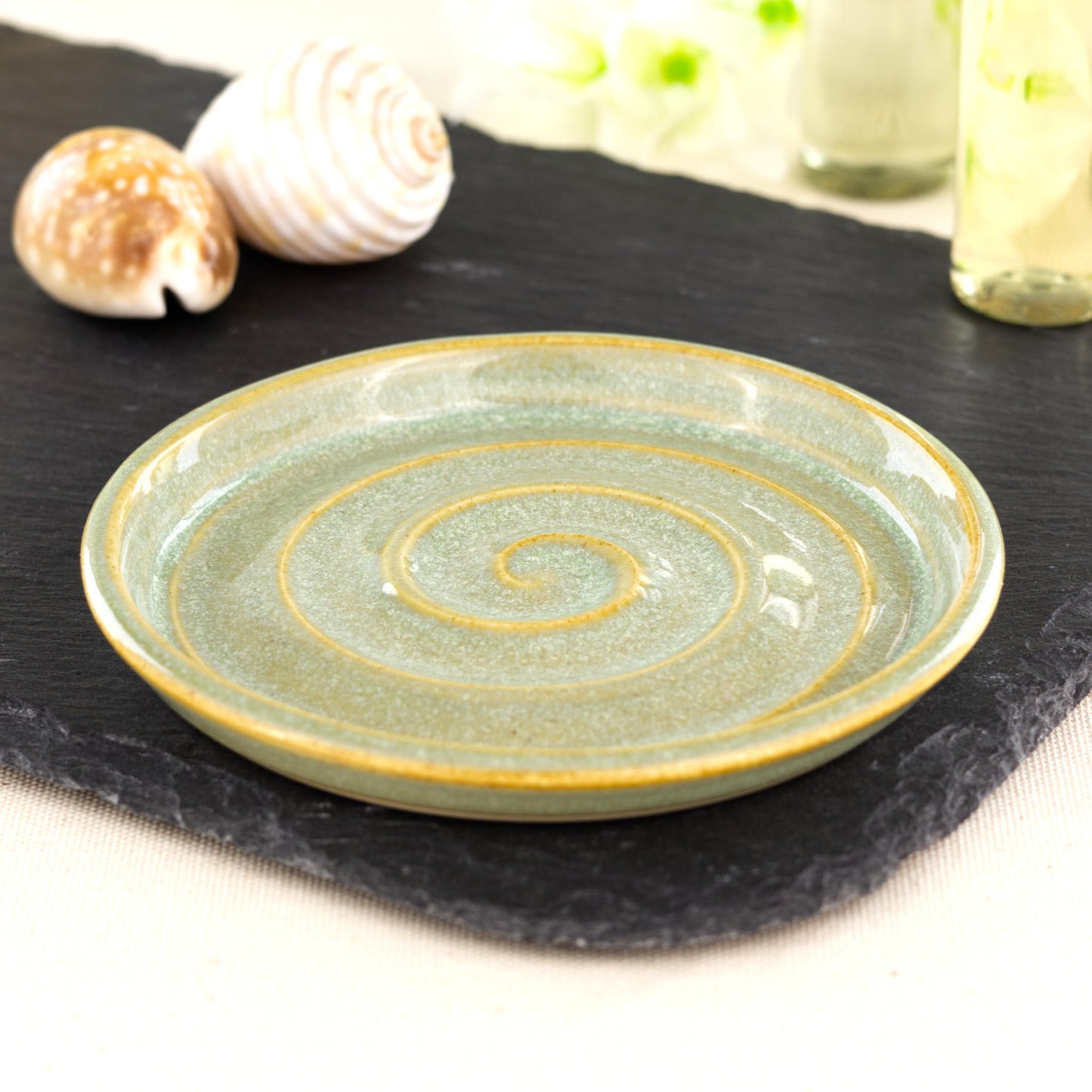 Handmade pale green ceramic soap dish with spiral ridges on slate board