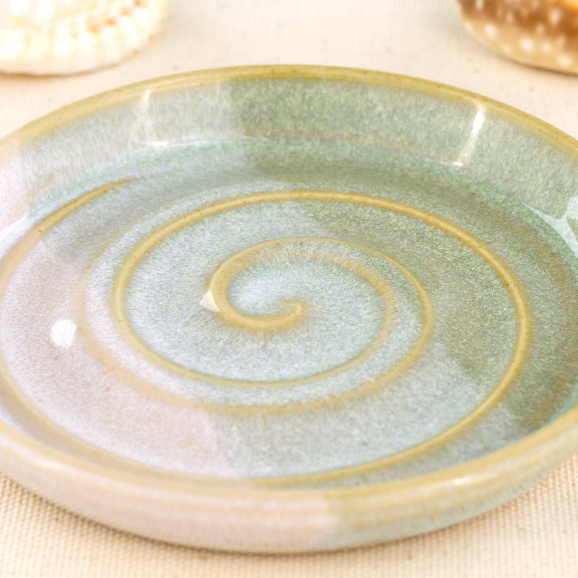 Close up of pale green and white soap dish, overlapping glazes with striped spiral design and glossy Sea Smoothed Pebble finish