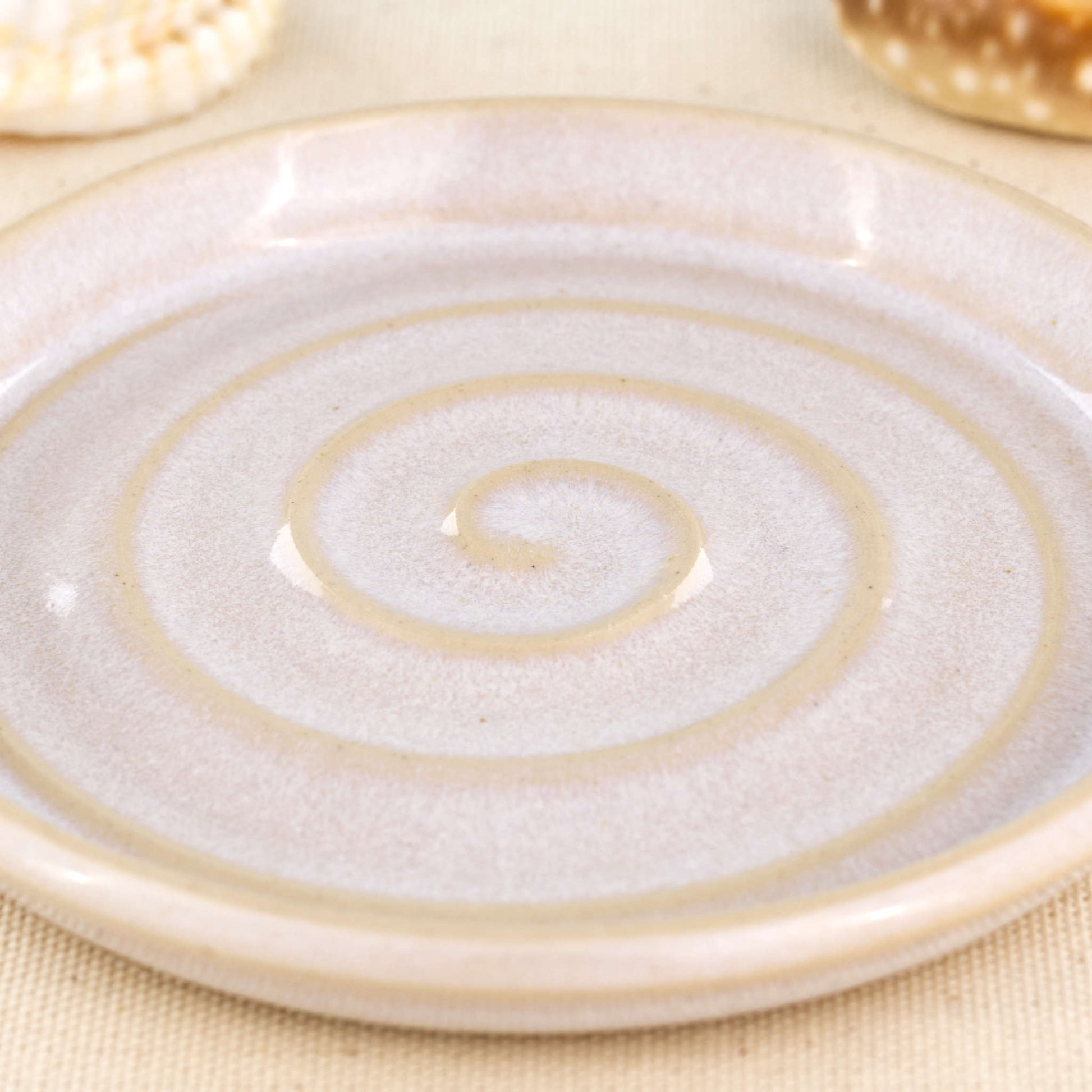 Close up of white glazed ceramic soap dish with spiral pattern, speckled handmade stoneware soap saver tray