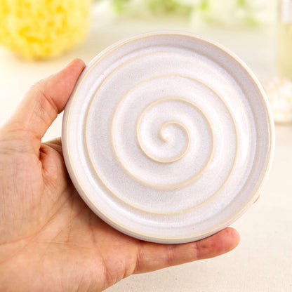 White handmade pottery soap dish held in hand showing size, spiral draining design, artisan ceramic soap holder for sink or shower