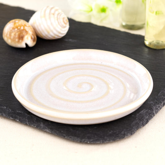 Handmade white ceramic soap dish with spiral ridges, wheel-thrown stoneware bathroom accessory on black slate with coastal shell styling