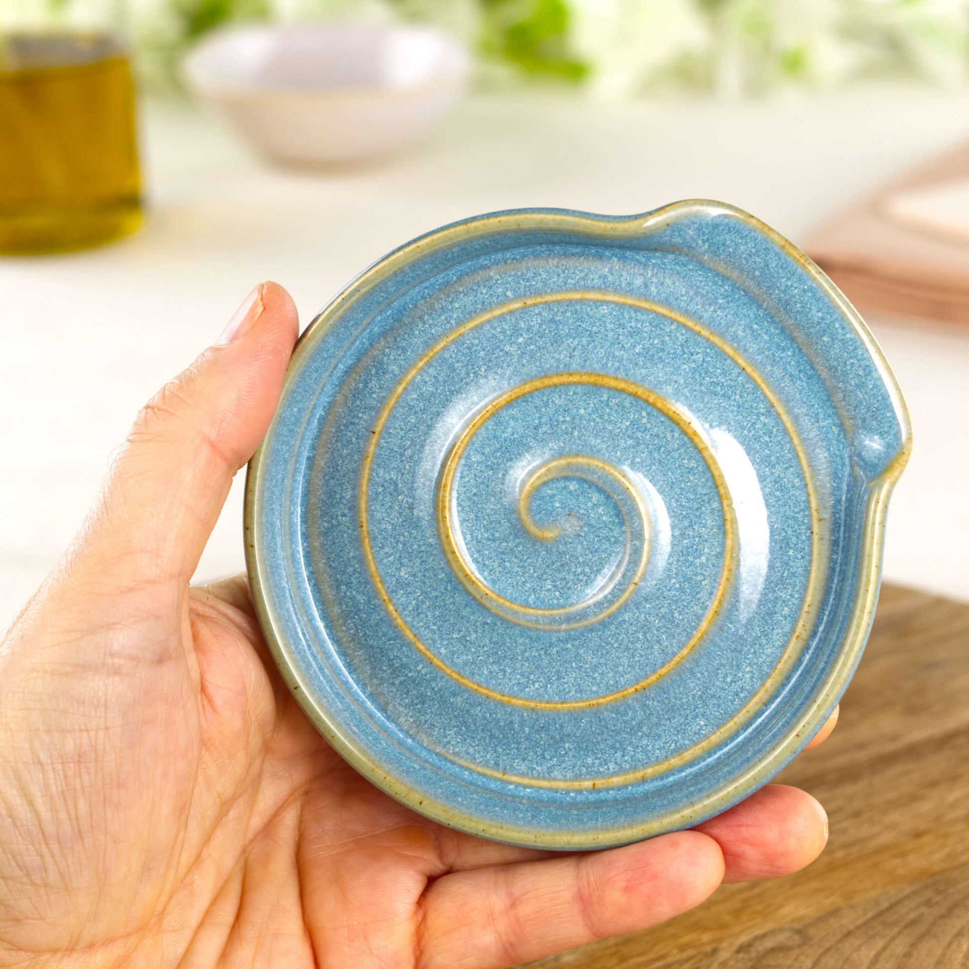 Handmade Coastal Blue spoon rest shown in hand, compact wheel-thrown ceramic spoon holder for kitchen counter or hob side