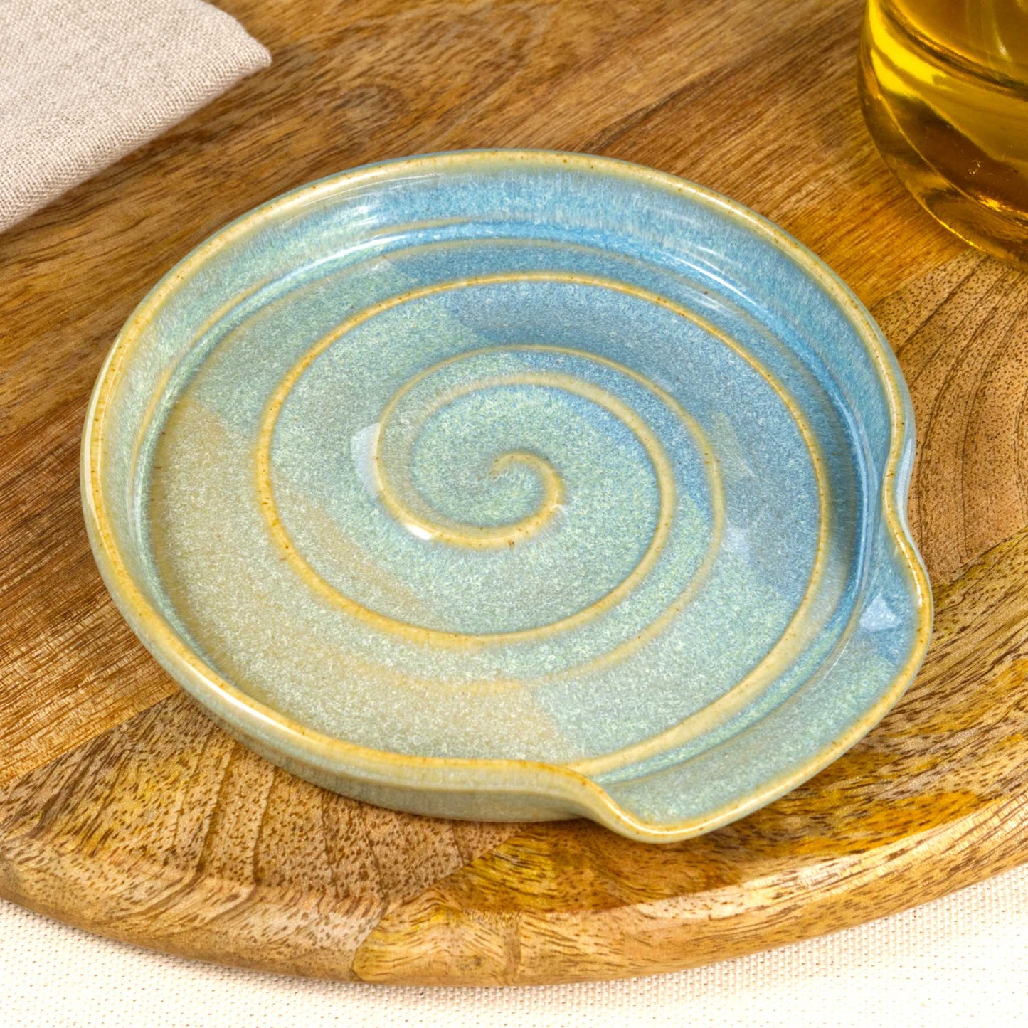 Close up of Coastal Blue and Pale Green pottery spoon rest with glossy speckled glaze, handmade ceramic utensil rest with spiral detail