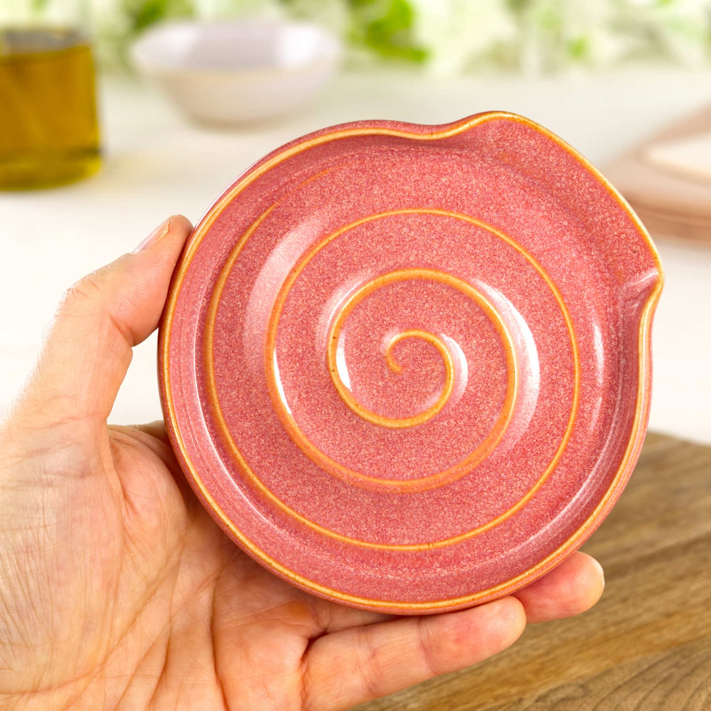 Handmade Coral spoon rest shown in hand, compact wheel-thrown ceramic spoon holder for kitchen counter or hob side