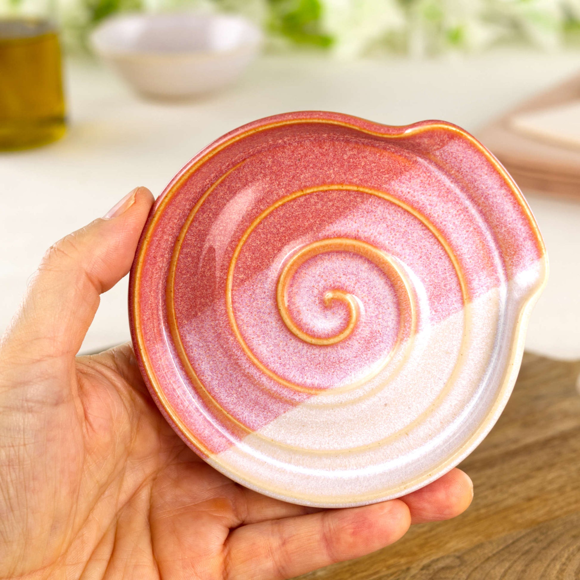 Coral and White pottery spoon rest shown in hand, compact handmade kitchen spoon holder for hob side cooking