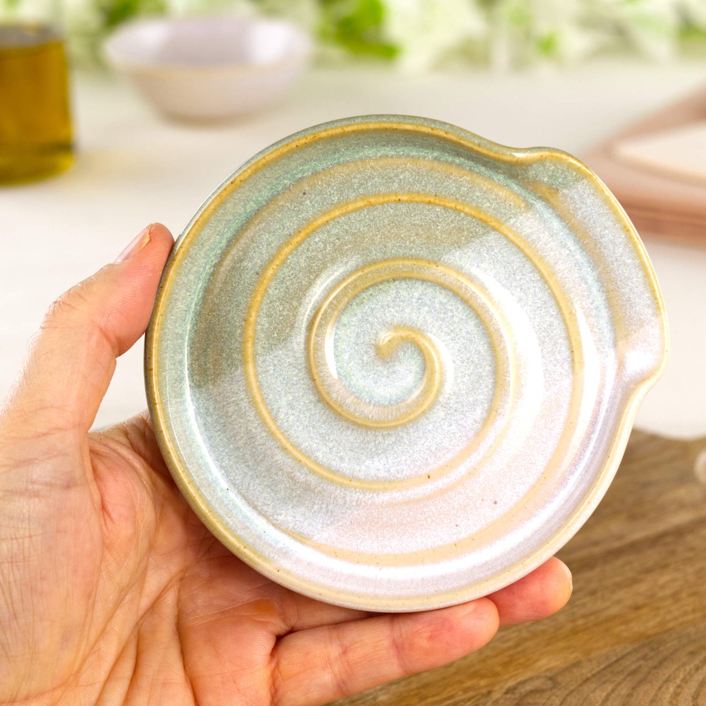 Pale Green and White pottery spoon rest shown in hand, compact handmade kitchen spoon holder for hob side cooking