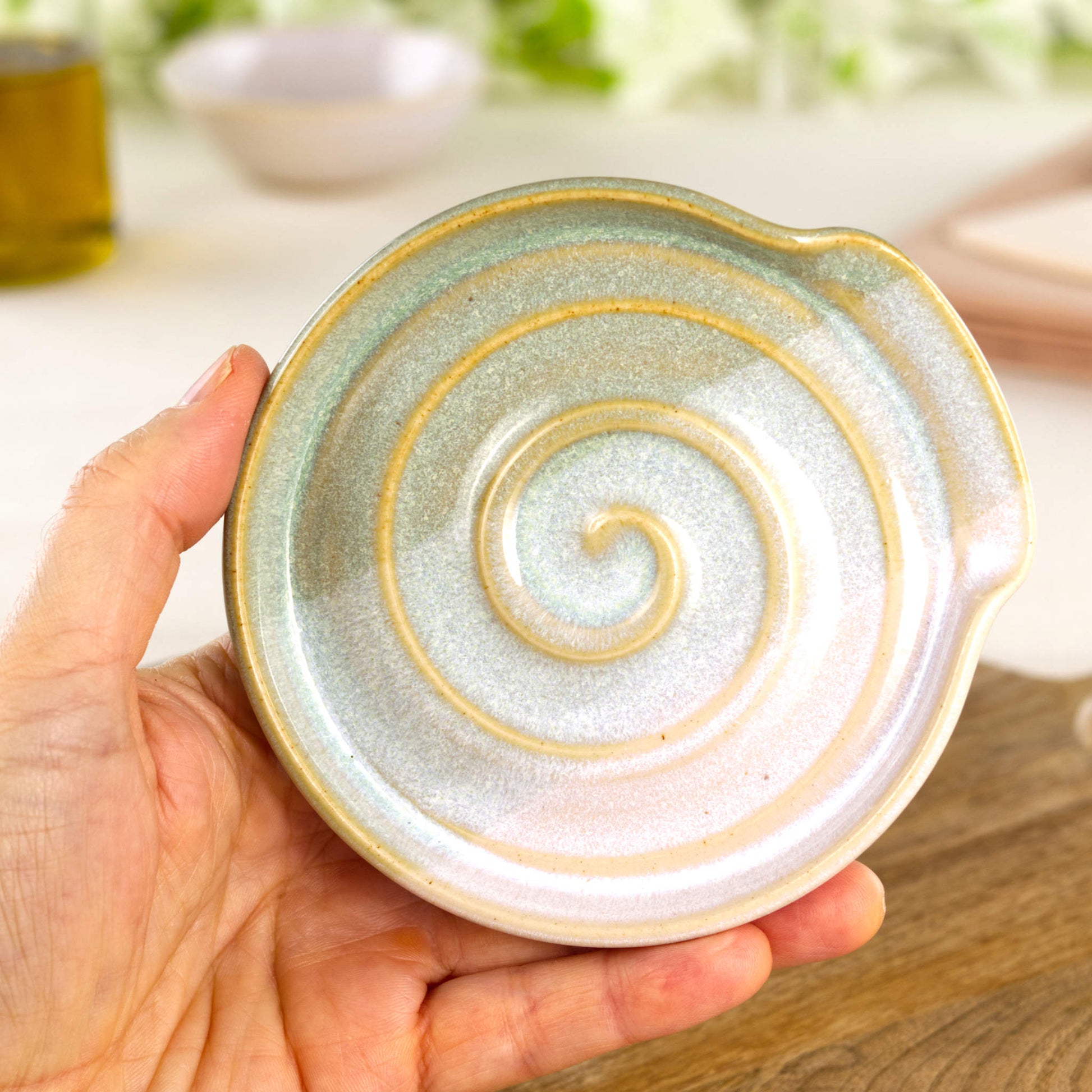 Pale Green and White pottery spoon rest shown in hand, compact handmade kitchen spoon holder for hob side cooking
