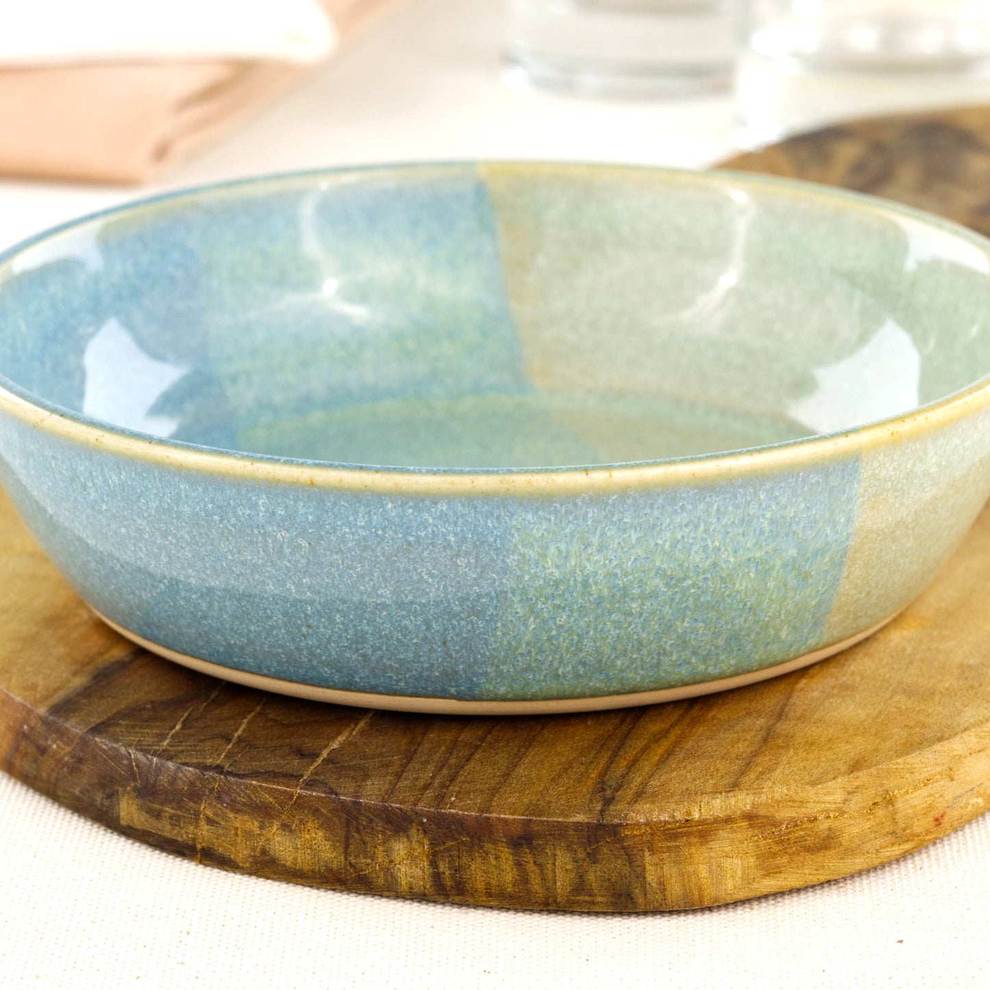 Close-up of a handmade stoneware tapas bowl in Coastal Blue & Pale Green, highlighting the glossy speckled glaze, layered coastal tones and shallow shape for dips, olives and mezze