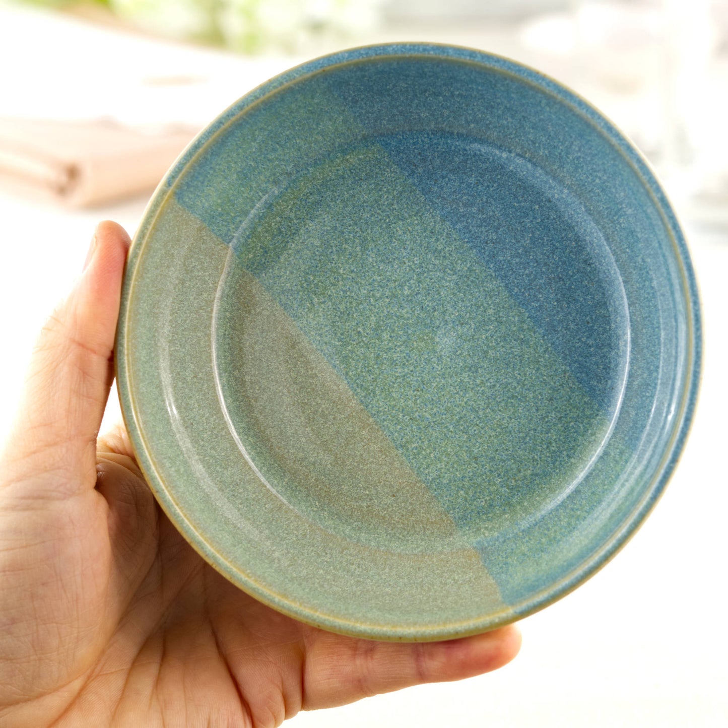 Handmade ceramic tapas bowl held in the hand, finished in Coastal Blue & Pale Green glazes with a flatter interior designed for tapas-style serving, side dishes and sharing food