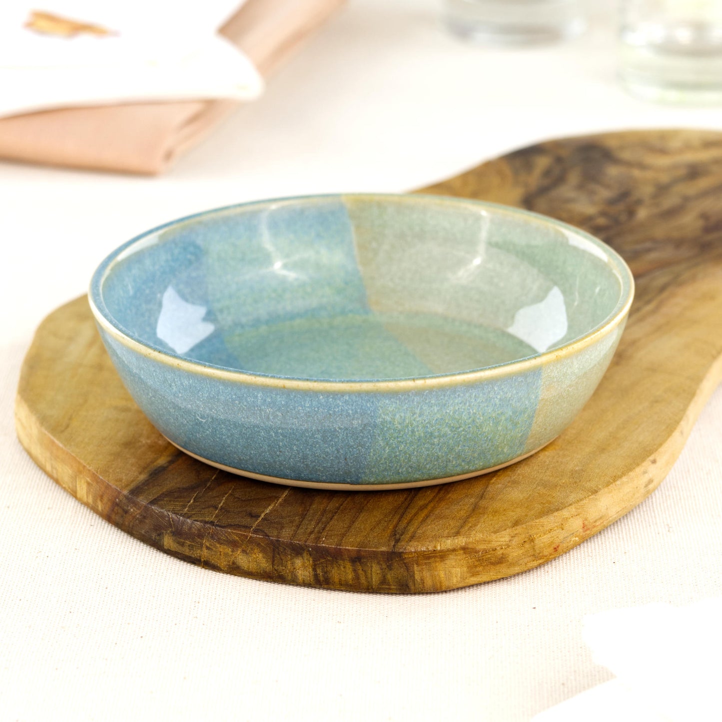 Wheel-thrown Coastal Blue & Pale Green tapas bowl on an olive wood board, a piece of British studio pottery for tapas, grazing platters, picky bits and everyday artisan tableware