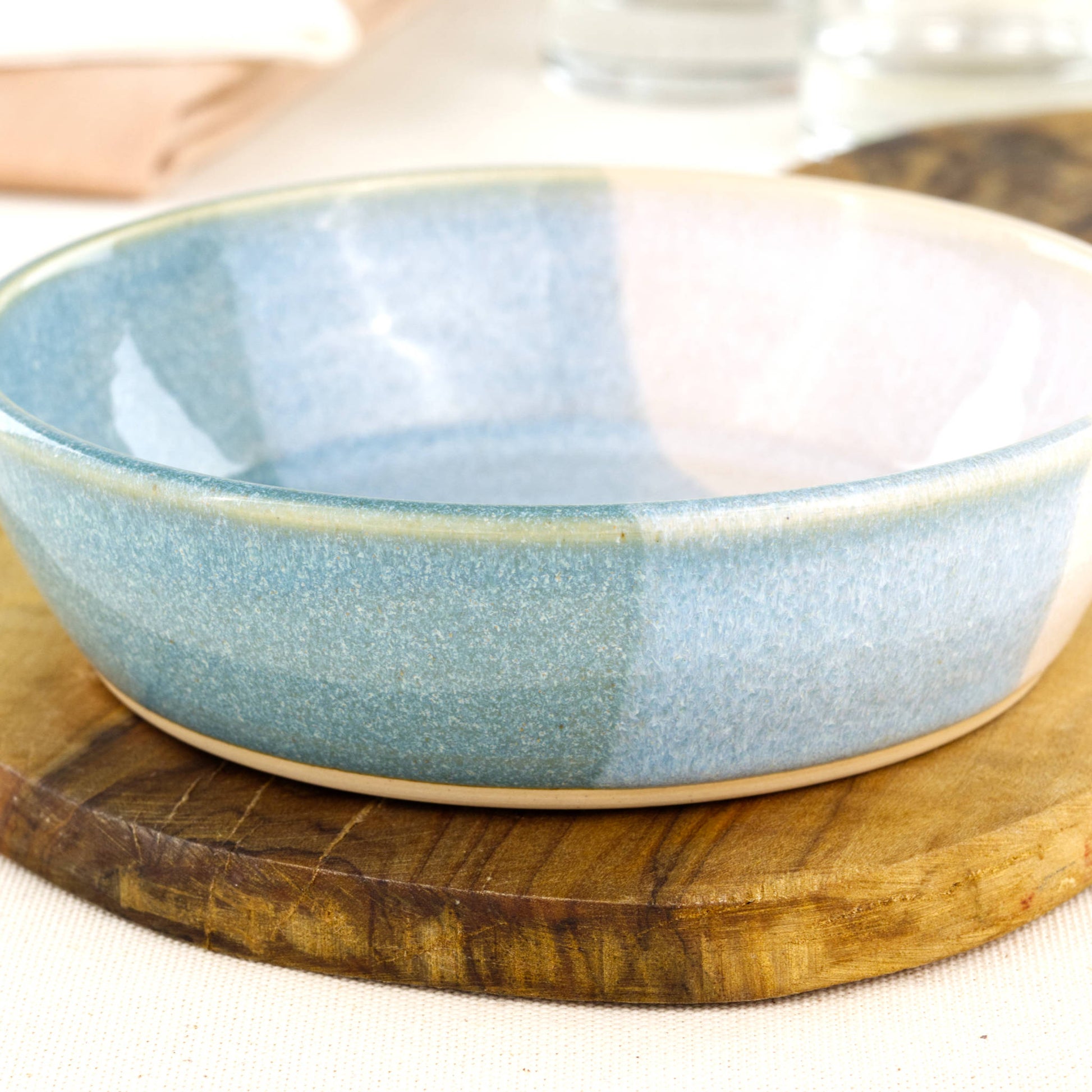 Close-up of a handmade stoneware tapas bowl in Coastal Blue & White, showing the glossy speckled glaze and shallow serving bowl shape