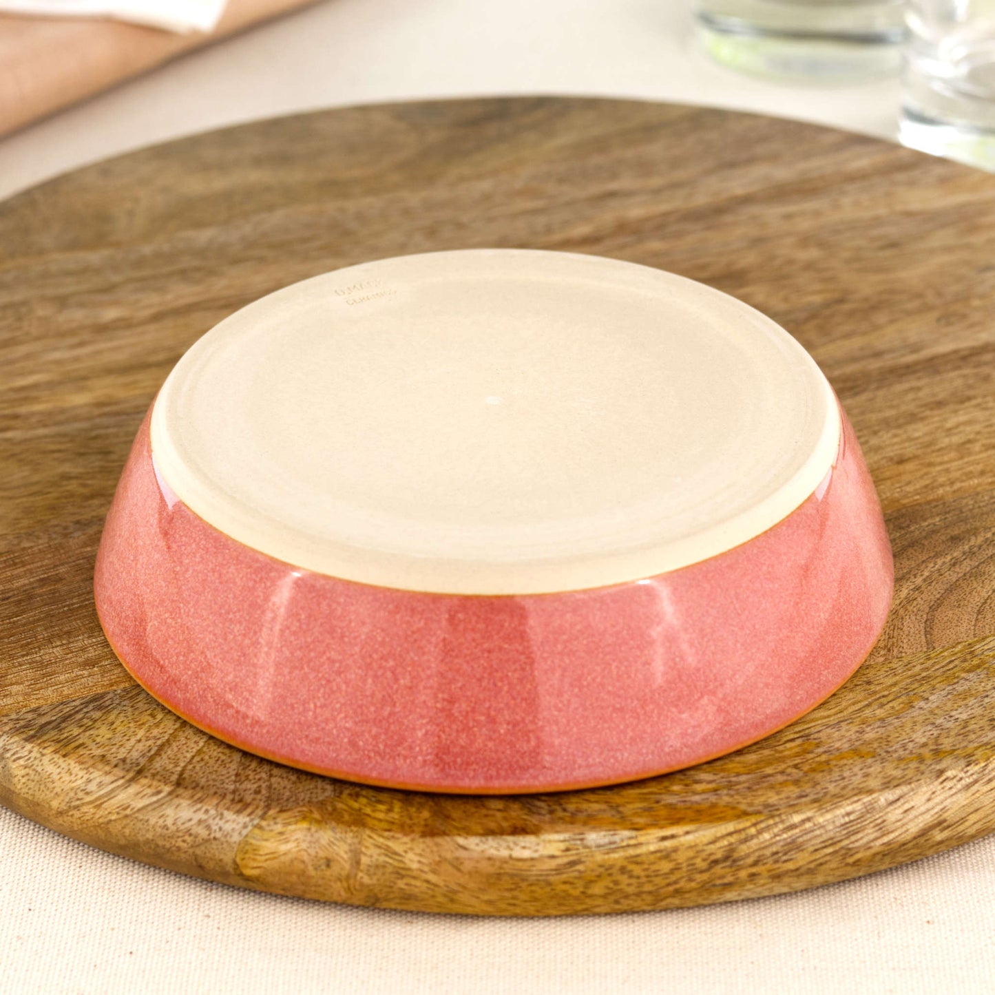 Base of a wheel-thrown Coral tapas bowl, showing the smooth burnished foot and makers mark, handmade in a small Sussex pottery studio