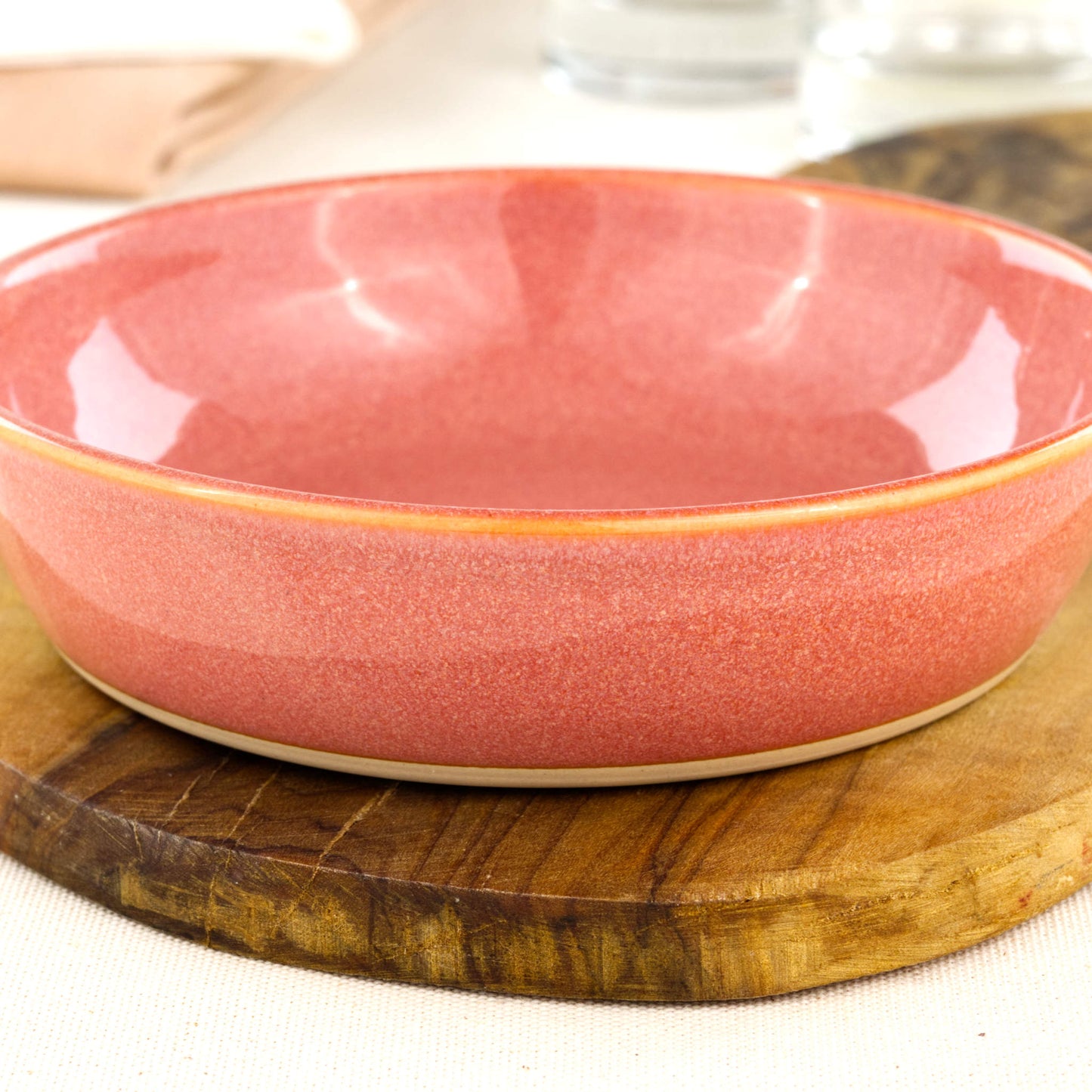 Close-up of a handmade stoneware tapas bowl in Coral, highlighting the glossy speckled glaze, warm peachy tones and flatter shape designed for tapas-style serving
